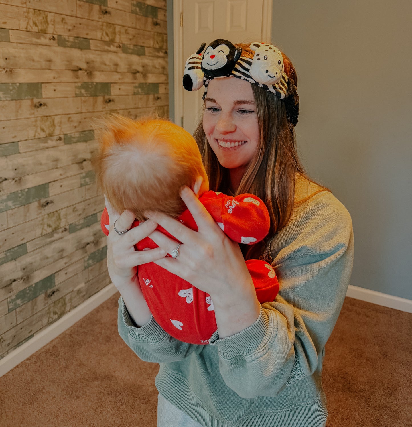 parent wearing high-contrast headband and sensory baby toy while holding baby for face-to-face interaction