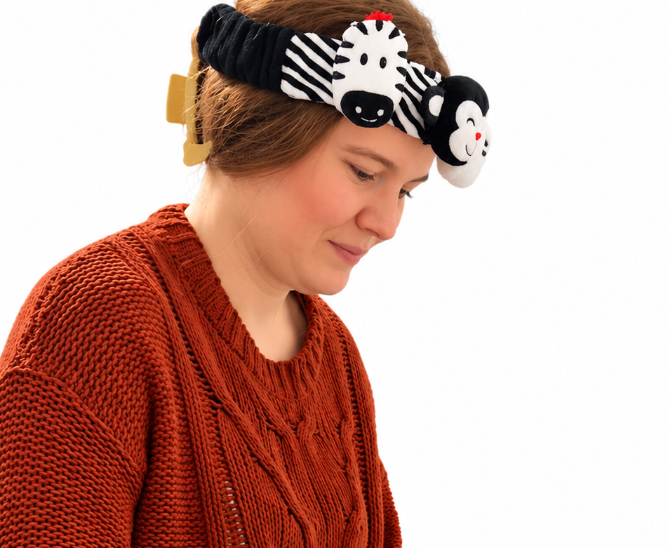 a mom wearing the looky baby headband to help with her fussy and wiggly baby during diaper changes. the high-contrast sensory headband designed by an occupational therapist for newborns to encourage visual development and engagement. it is a caregiver-worn baby distraction headband for diaper changes and daily routines. 