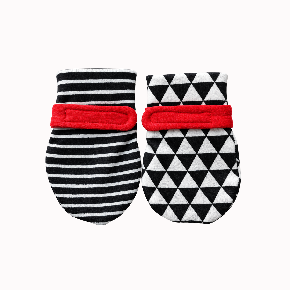 A pair of soft high-contrast baby mittens with black and white patterns and red accents, displayed against a clean white background.