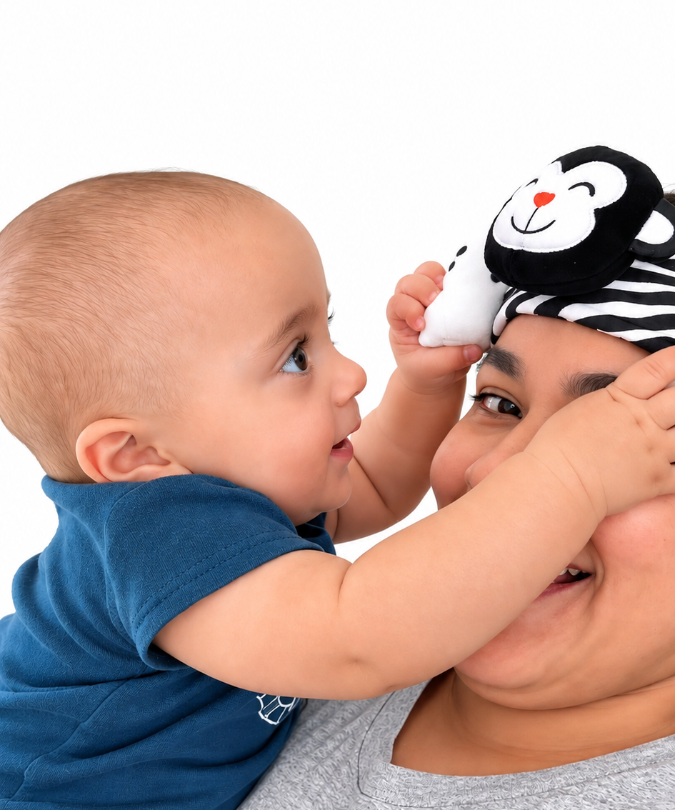 a mom wearing looky baby the high-contrast sensory headband designed by an occupational therapist for newborns to encourage visual development and engagement. it is a caregiver-worn baby distraction headband for diaper changes and daily routines. the headband is made of soft fabric with black and white  patterns and animal characters to grab a baby's attention. the baby is looking at the headband and smiling and playing with it.