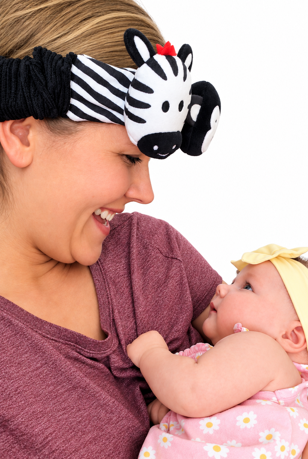 a mom wearing looky baby the high-contrast sensory headband designed by an occupational therapist for newborns to encourage visual development and engagement. it is a caregiver-worn baby distraction headband for diaper changes and daily routines. the headband is made of soft fabric with black and white  patterns and animal characters to grab a baby's attention. the baby is looking at the headband and smiling. 