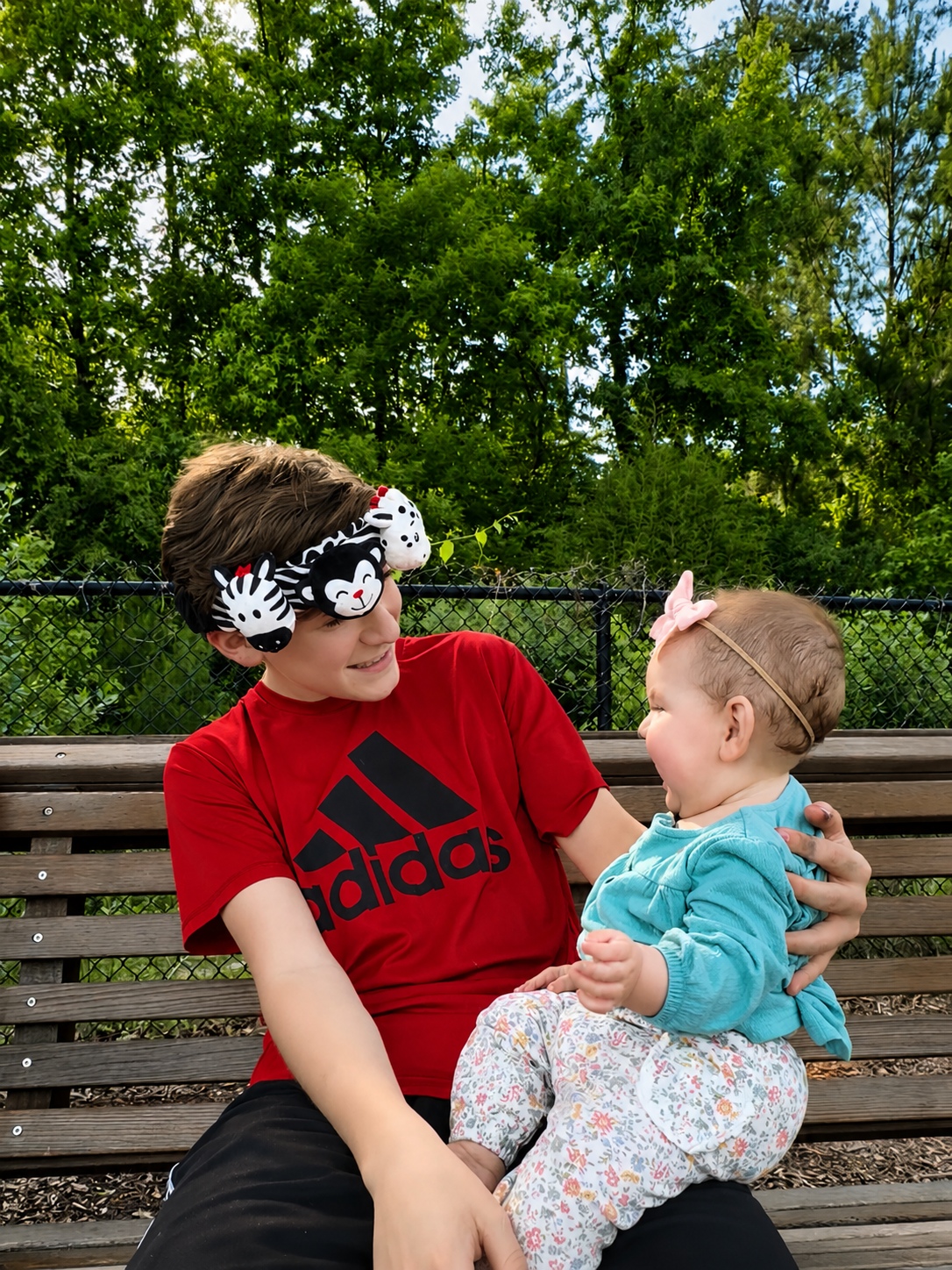 a big brother wearing the looky baby high contrast sensory headband toy while playing with his newborn sister 